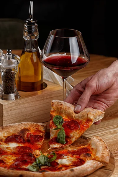 Biberli pizza ve ahşap masada bir bardak şarap.