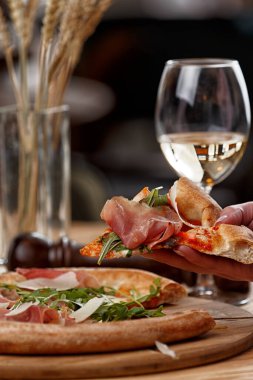 Jamonlu pizza ve ahşap bir masada otlar.