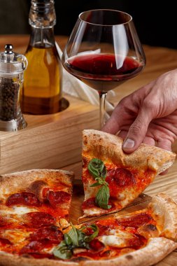 Biberli pizza ve ahşap masada bir bardak şarap.