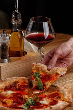 Biberli pizza ve ahşap masada bir bardak şarap.