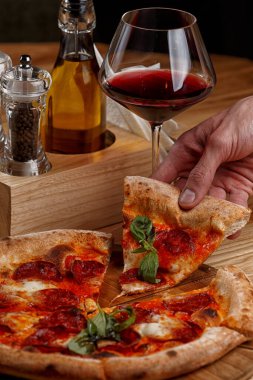 Biberli pizza ve ahşap masada bir bardak şarap.