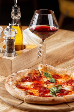 Biberli pizza ve ahşap masada bir bardak şarap.