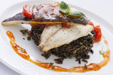 Kızarmış Dorado filetosu ve beyaz arka planda yaban pirinci.