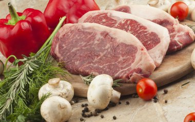 Çiğ et bifteği, yeşil mermer, domates ve mantarlar bir tabakta, seçici bir odak noktası.