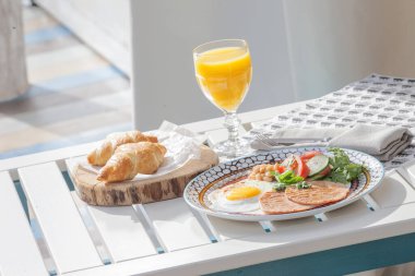 Kahvaltıda yumurta, kruvasan ve portakal suyu.