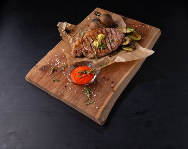 Tahta arka planda biftek ve taze patates.