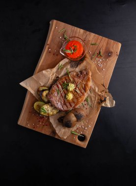 Tahta arka planda biftek ve taze patates.