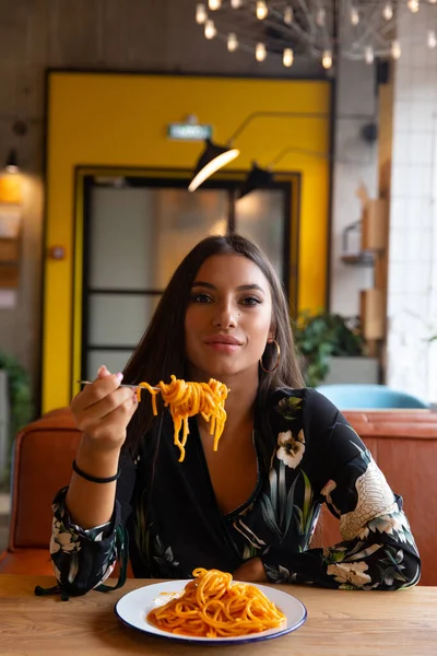 En ung flicka på ett kafé äter pasta — Stockfoto
