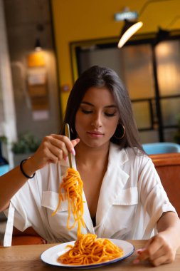 Bir kafede genç bir kız makarna yiyor.