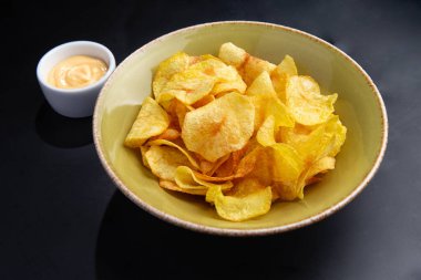 Koyu arkaplanda patates cipsi ve sos