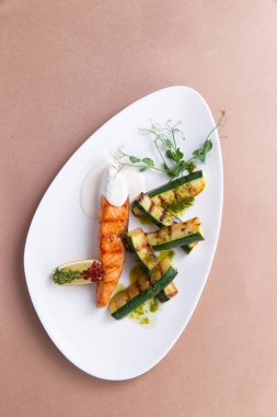 Tabakta ızgara somon ve kabak. kahverengi bir arkaplanda