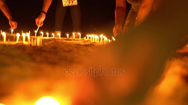 Las velas asiáticas sobre la arena en la ceremonia religiosa, ventoso. La gente enciende velas. Movimiento lento — Vídeos de Stock