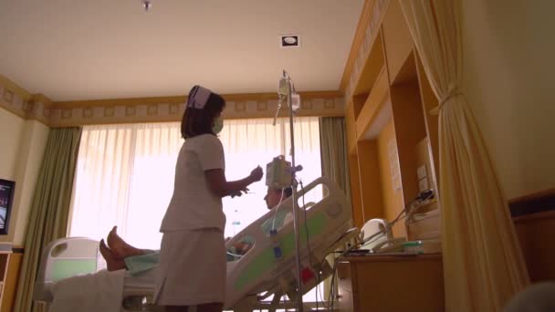 Женщина-медсестра проверяет капельницу лекарствами, оказывает первую помощь пациенту — стоковое видео