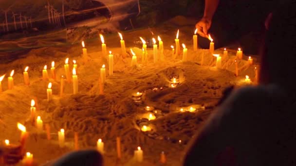 Aziatische kaarsen op zand in religieuze ceremonie, winderig. Slow motion — Stockvideo