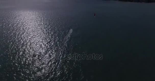 Aerial view of kitesurfer gliding across blue ocean, extreme sport drone footage 4K — Stock Video