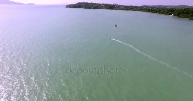Kitesurfing tropik adada. Havadan görünümü: kitesurfer deniz binici ile yüksek hızda gidiyor. Seyahat kavramı. Tayland Phuket. 4k video