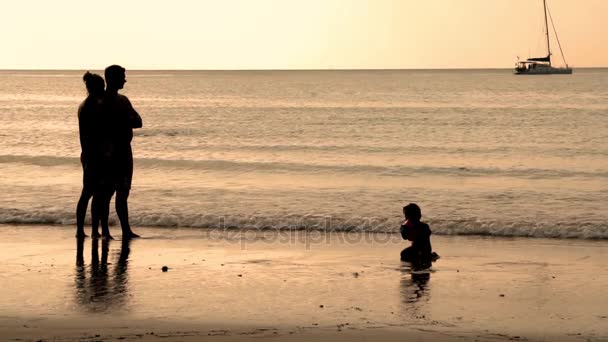 Szczęśliwa rodzina z dzieckiem na wakacje na plaży. Na zachód słońca. Slowmotion. 1920 x 1080 — Wideo stockowe