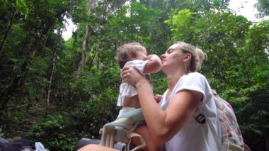 Genç anne ve küçük kızı ormanda dinleniyor. Gitar annem için göl kıyısında oynayan güzel çocuk.