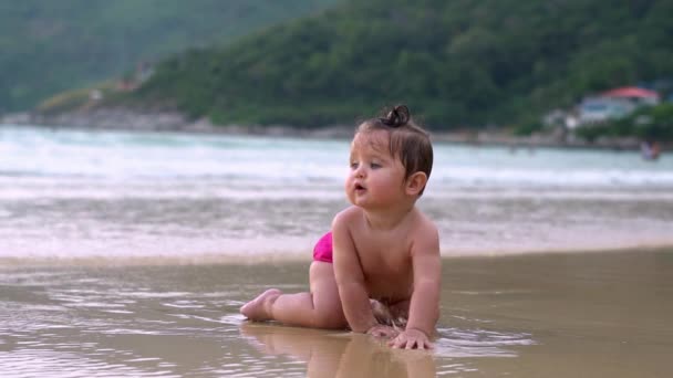 かわいい赤ちゃん、ビーチに座っていると波を楽しむ — ストック動画