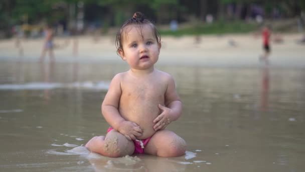 Sladké dítě sedí na pláži a užívat si vlny — Stock video