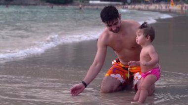 Mutlu bir aile deniz kıyısında yürüyüş. Kumsalda oynarken şirin bebek