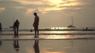 Mutlu bir aile deniz kıyısında yürüyüş. Siluetleri günbatımı.