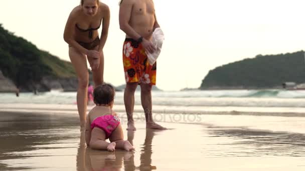 Glückliche Familie zu Fuß an der Küste. Niedliches kleines Baby spielt am Strand — Stockvideo