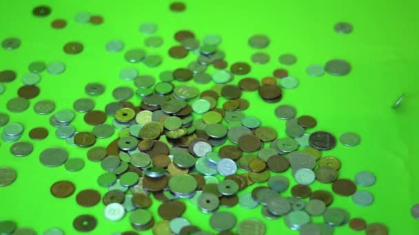 Монеты падают на зеленый фон, замедленная съемка — стоковое видео