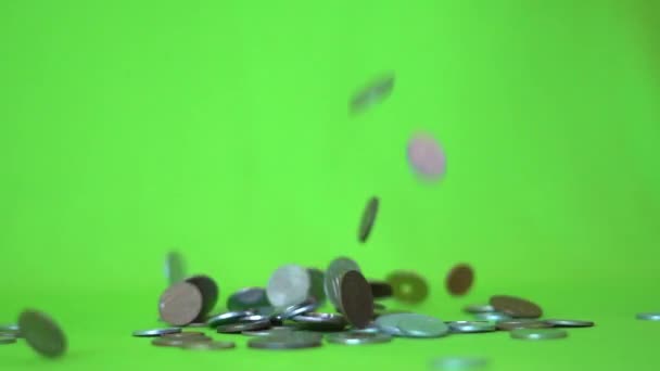 Monedas cayendo sobre un fondo verde, cámara lenta — Vídeos de Stock