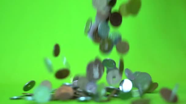 Munten die vallen op een groene achtergrond, slow-motion — Stockvideo