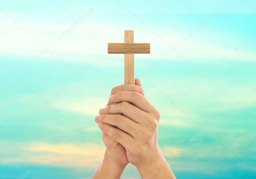 Human hands holding a cross 
