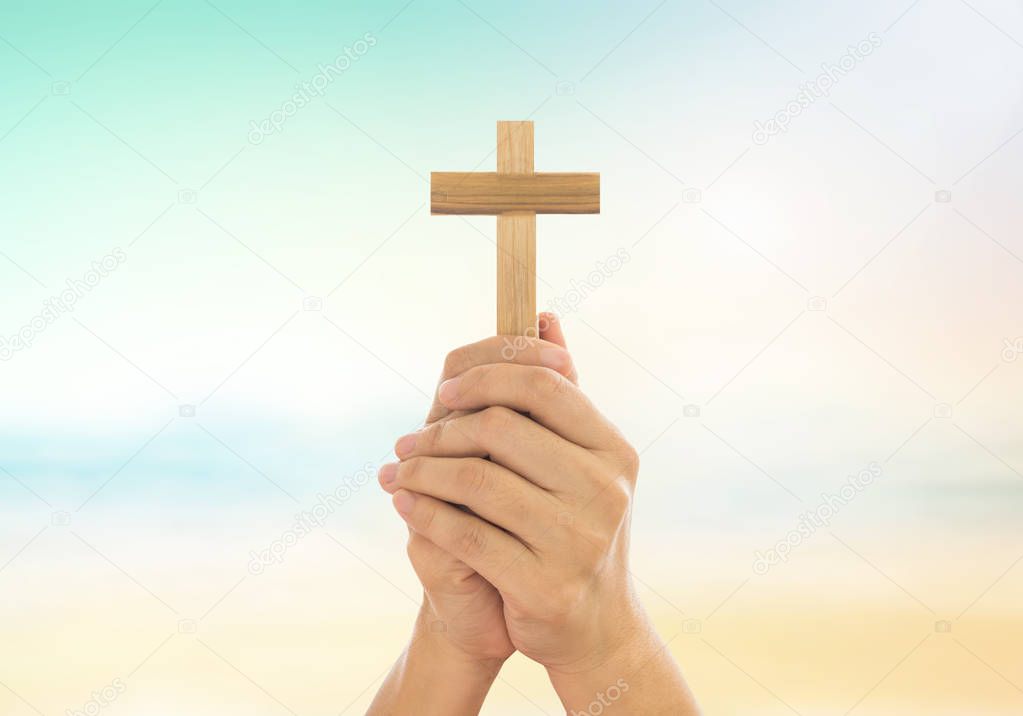 Human hands holding a cross 