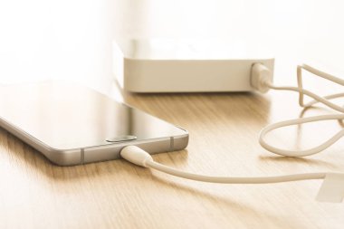 Mobil akıllı telefonlar ahşap masada enerji bankasıyla şarj oluyor.