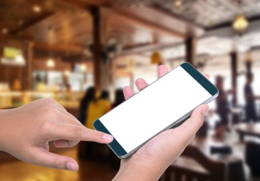 İnsan el tutma ve dokunmatik ekran akıllı telefon, tablet, kafe arka planda bulanık cep telefonu; Ekranda akıllı telefon kırpma yolu ile. reklamınız için boş ekran.