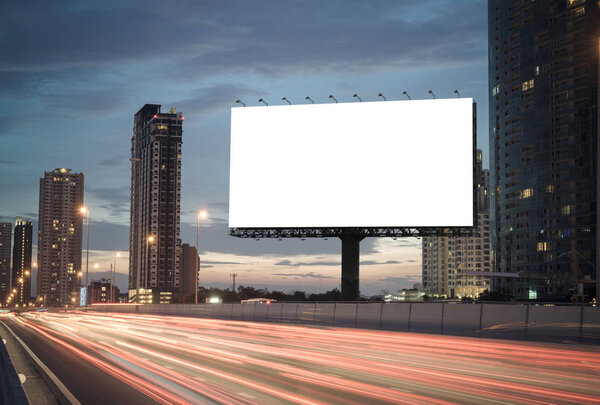 blank billboard on the highway, blank billboard during the twilight light, blank billboard in city background. With clipping path on screen.- can be used for display your products or promotional