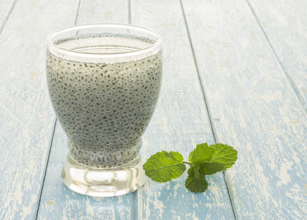 Sweet basil seed drink in glass of water on woodden background.