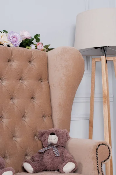 Toy bear on a brown sofa near the lamp — Stock Photo, Image