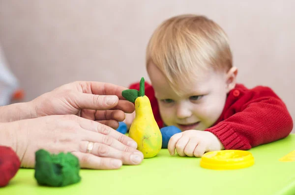 Manos masculinas muestran la pera de plastilina del niño — Foto de Stock