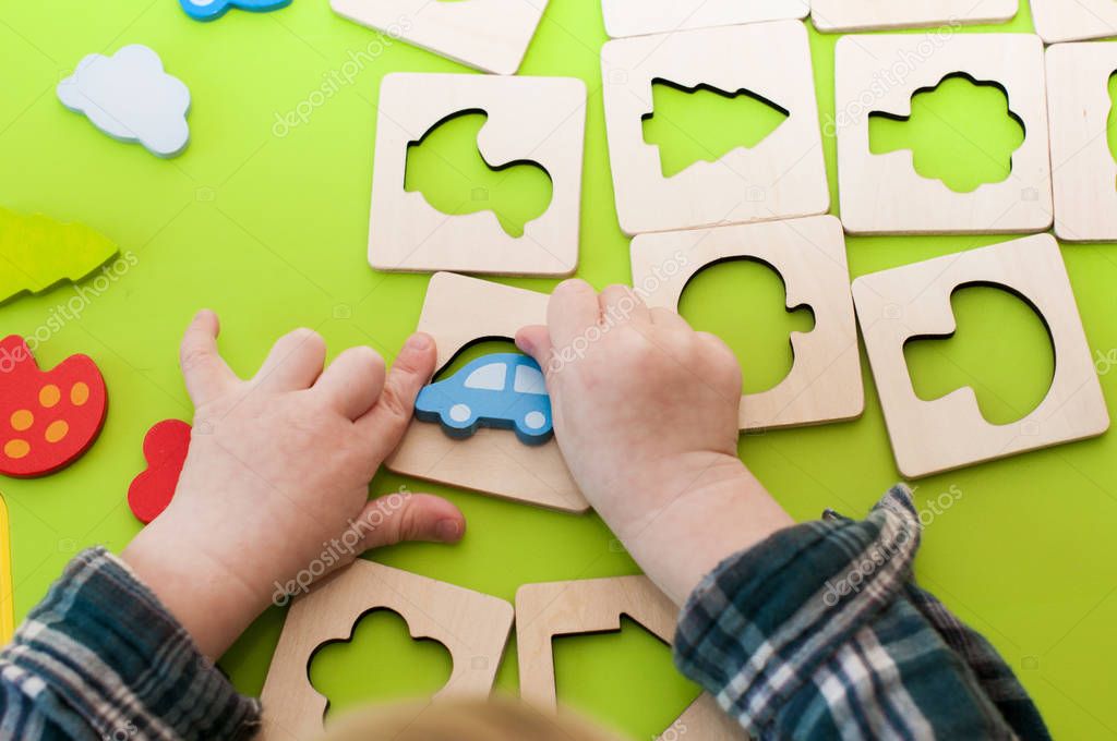 children's hands playing with wooden shape sorter 