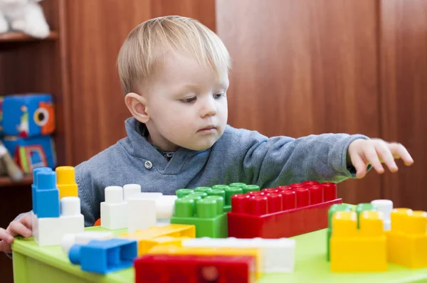 Niño pequeño que busca un constuctor de juguete en interiores — Foto de Stock
