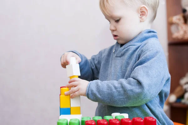 Niño construye una pirámide con constructor de plástico de color — Foto de Stock