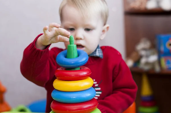 Niño añade una pirámide de anillos de colores — Foto de Stock