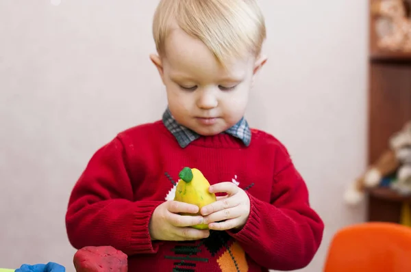 Plastilina de pera amarilla en manos de niños — Foto de Stock