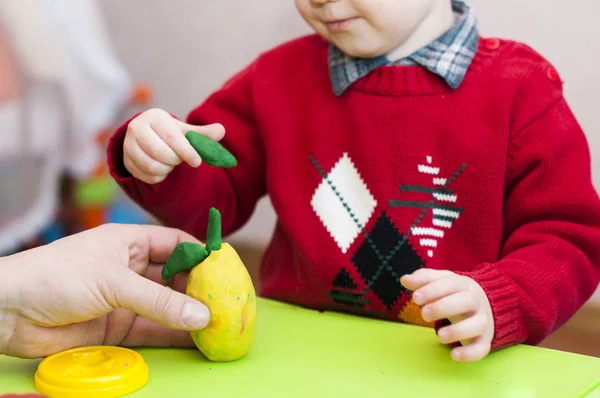 Un niño con una pera adulta esculpe de arcilla — Foto de Stock