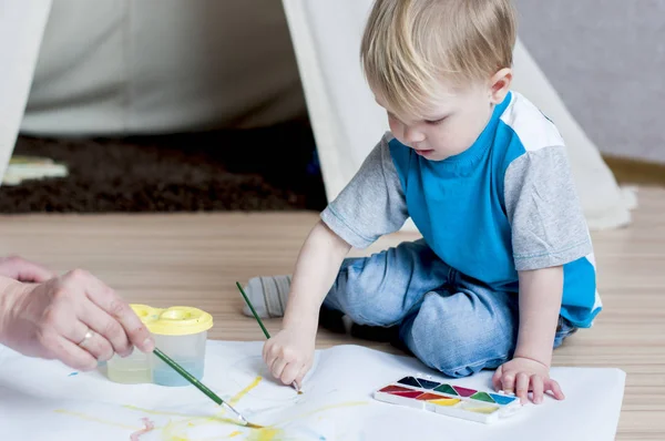 Encantador niño intenta pintar con acuarelas — Foto de Stock