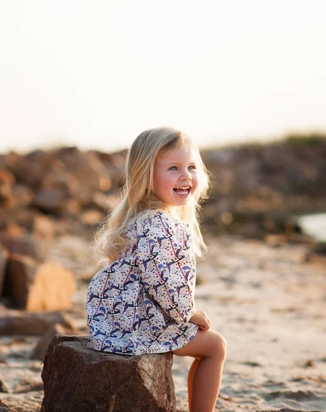 Portret van een lachende klein meisje op een steen — Stockfoto