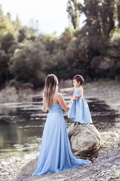 Mooie moeder met kleine dochter in blauwe identieke jurken — Stockfoto