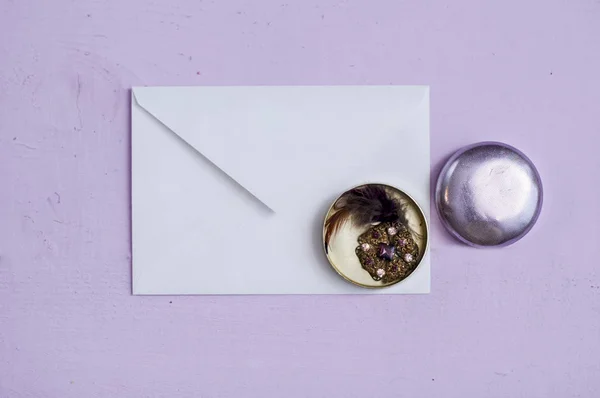 白色信封与珠宝在一个圆的金属箱子平放置在紫色背景 — 图库照片