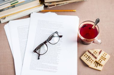 gözlük, bir ev, kalem, kitap, şeklinde kurabiye kurabiye ile bir cam kabın içinde blueberry çay belgelerle düz yatıyordu