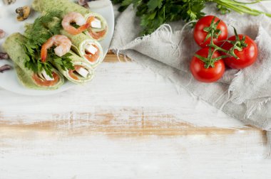 Krep ıspanak ve içinde sarılı somon ile domates gri peçete, düz ahşap zemin üzerinde yatıyordu..